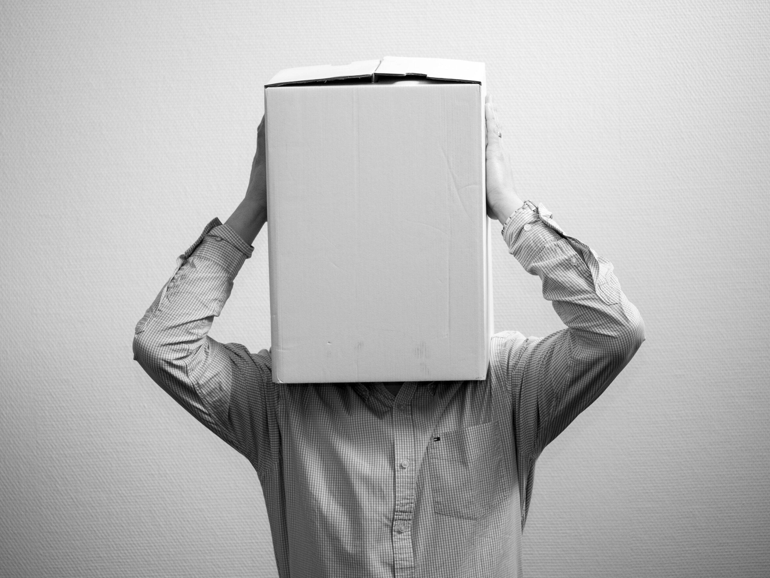 Man in long sleeve shirt with box on top of his head