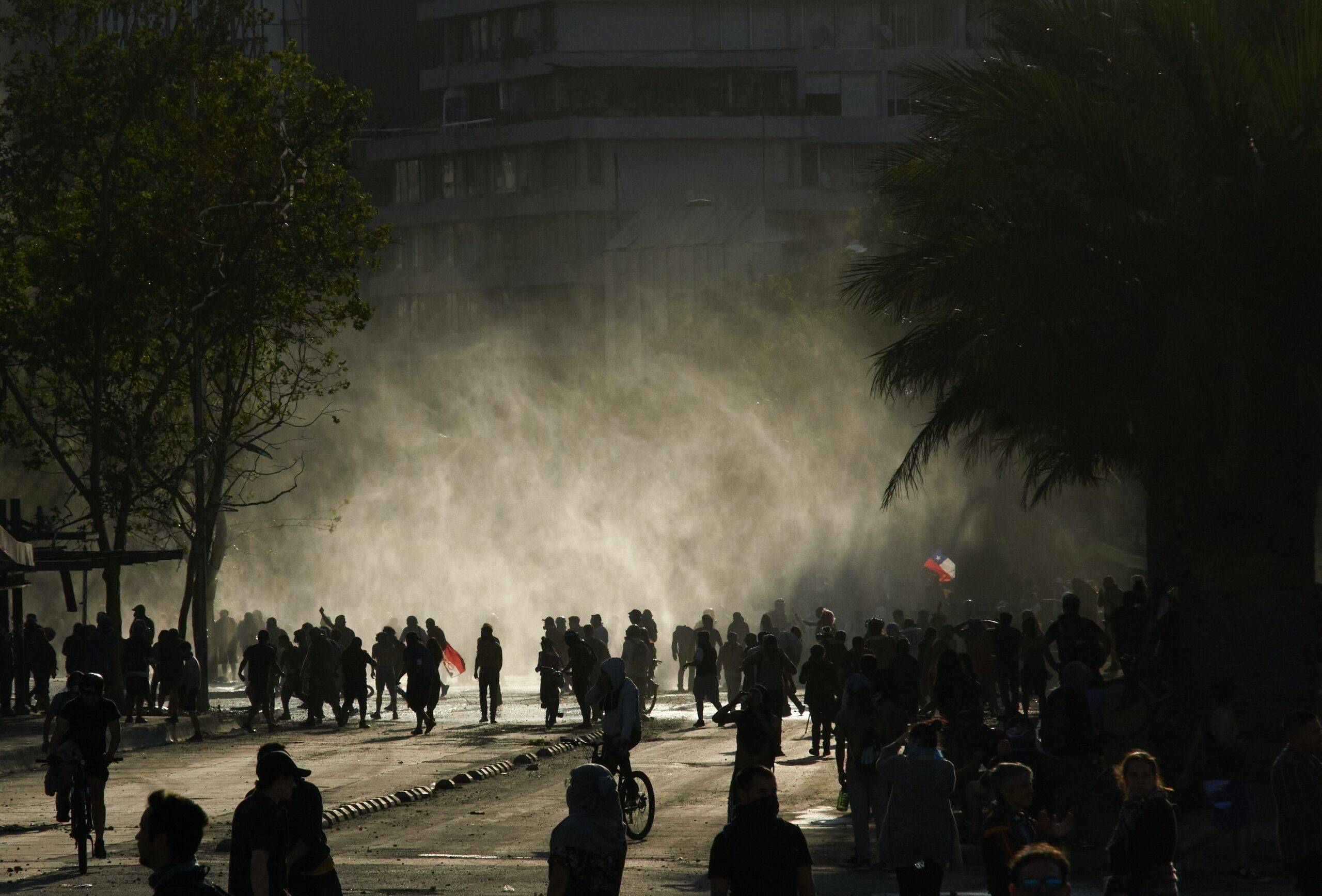 dark scene of people gathering on the streets with smoke in the background