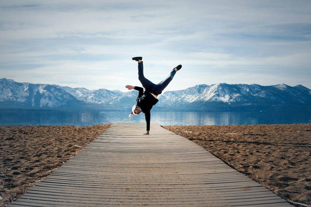 guy doing a handstand on a dock by a mountain lake