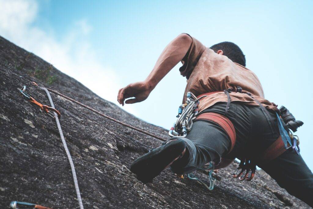 person climbing a granite surface with climbing gear
